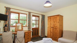Ein Hotelzimmer mit Bett, Schreibtisch, Stuhl, Kleiderschrank und Fernseher.
