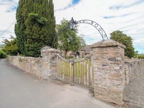 A stone gate with a wooden fence, a lamp post, and a tall tree in the background. - Apartment 3 (Lydbury North)