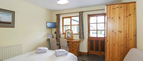 A bedroom with a bed, a desk, a chair, a wardrobe, and a television.