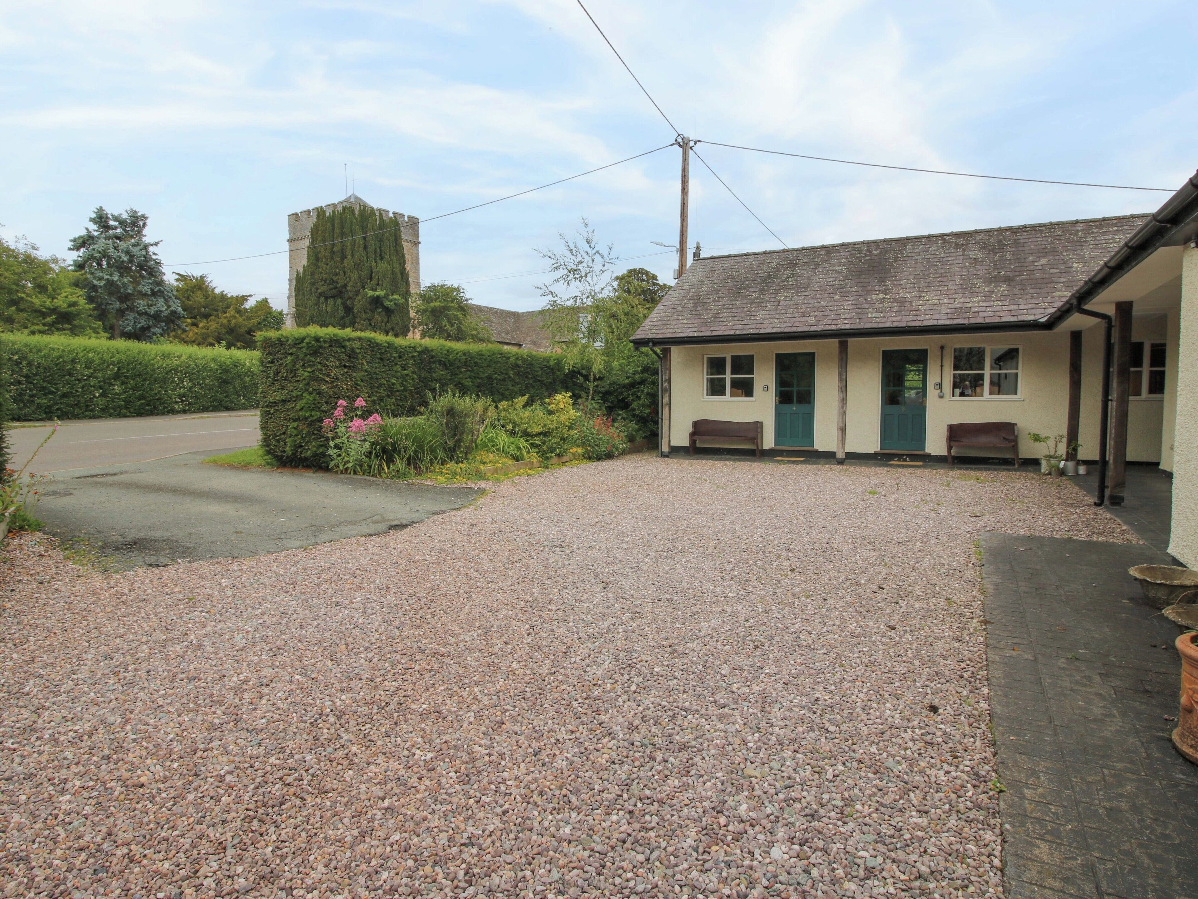 A building with a gravel driveway, a green door, and a bench outside.
