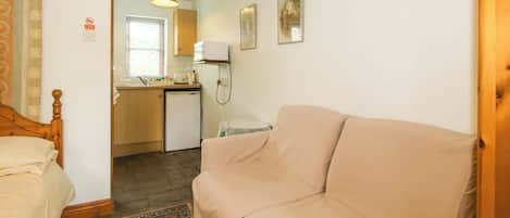 A compact room with a bed, a sofa, a kitchenette, and a small dining area.