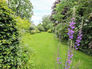 A well-maintained garden with a variety of plants and flowers, a neatly trimmed lawn, and a clear sky. - Apartment 2 (Lydbury North)