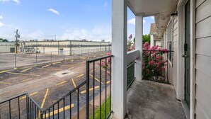 A building with a covered porch, a parking lot, and a clear sky. - Wilcrest Apartments by Andes STR (Houston)