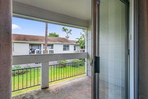 A covered porch with a view of a house, a metal railing, and a door. - Wilcrest Apartments by Andes STR (Houston)