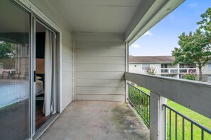 Ein Balkon mit Betonboden, Metallgeländer und Blick auf die Nachbargebäude.