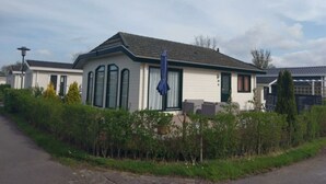 A single-story mobile home with a gabled roof, large windows, and a blue umbrella in front. - Holiday Home in Breskens With Terrace (Breskens)