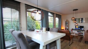 A modern living room with a dining table, chairs, a TV, and a bookshelf. - Holiday Home in Breskens With Terrace (Breskens)