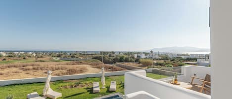 Une vue sur la piscine, avec un ciel dégagé, la piscine elle-même, des chaises longues et un paysage lointain.