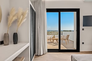 Ein modernes Schlafzimmer mit Balkon, Fernseher und Blick auf die Landschaft.