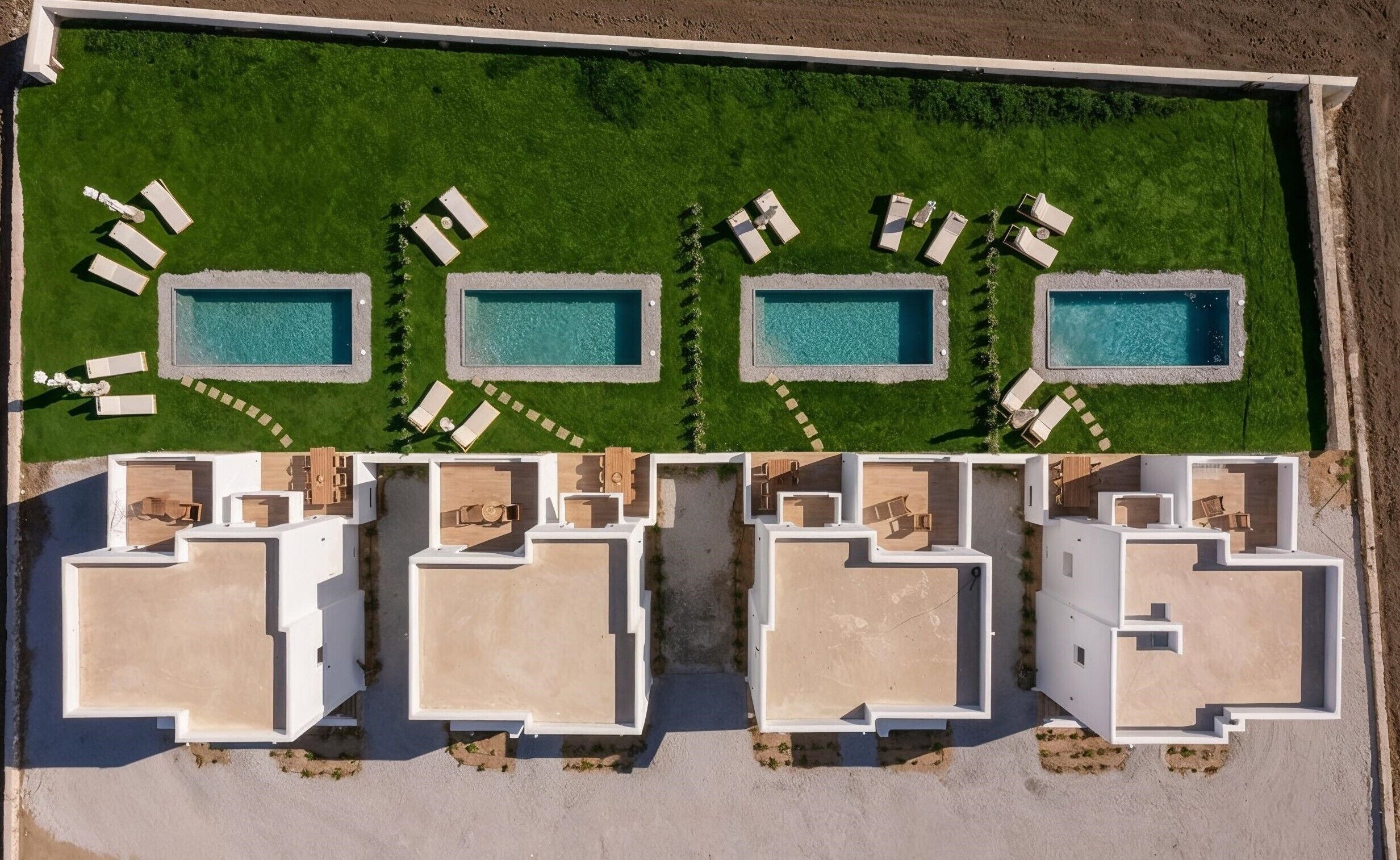 An aerial view of a resort with four swimming pools, each surrounded by lounge chairs and a small garden area.