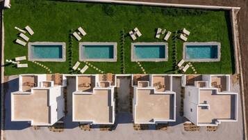 An aerial view of a resort with four swimming pools, each surrounded by lounge chairs and a small garden area.