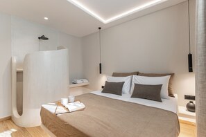 A modern bedroom with a large bed, a built-in shower, and a bedside table with a lamp. - Naxian Spirit Luxury Villas Plaka (Plaka)
