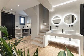 A modern bathroom with a large mirror, a sink, and a staircase leading to another level. - Naxian Spirit Luxury Villas Plaka (Plaka)