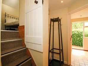 A staircase with a bed at the top, a white door, and a metal shelf unit. - Kwerky Cottage (Lydbury North)