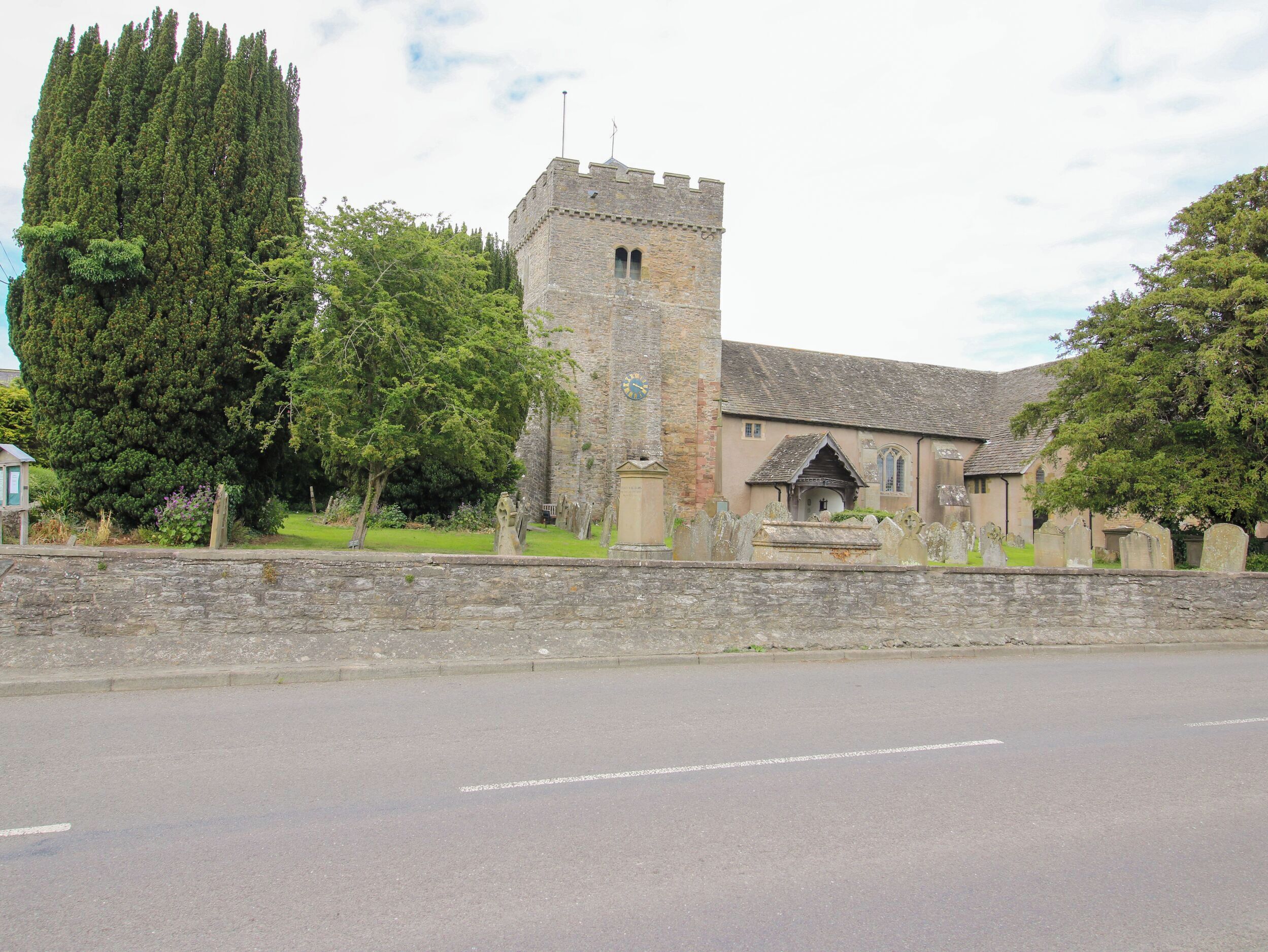 A historic building with a prominent tower, a church with a bell tower, and a cemetery with headstones.