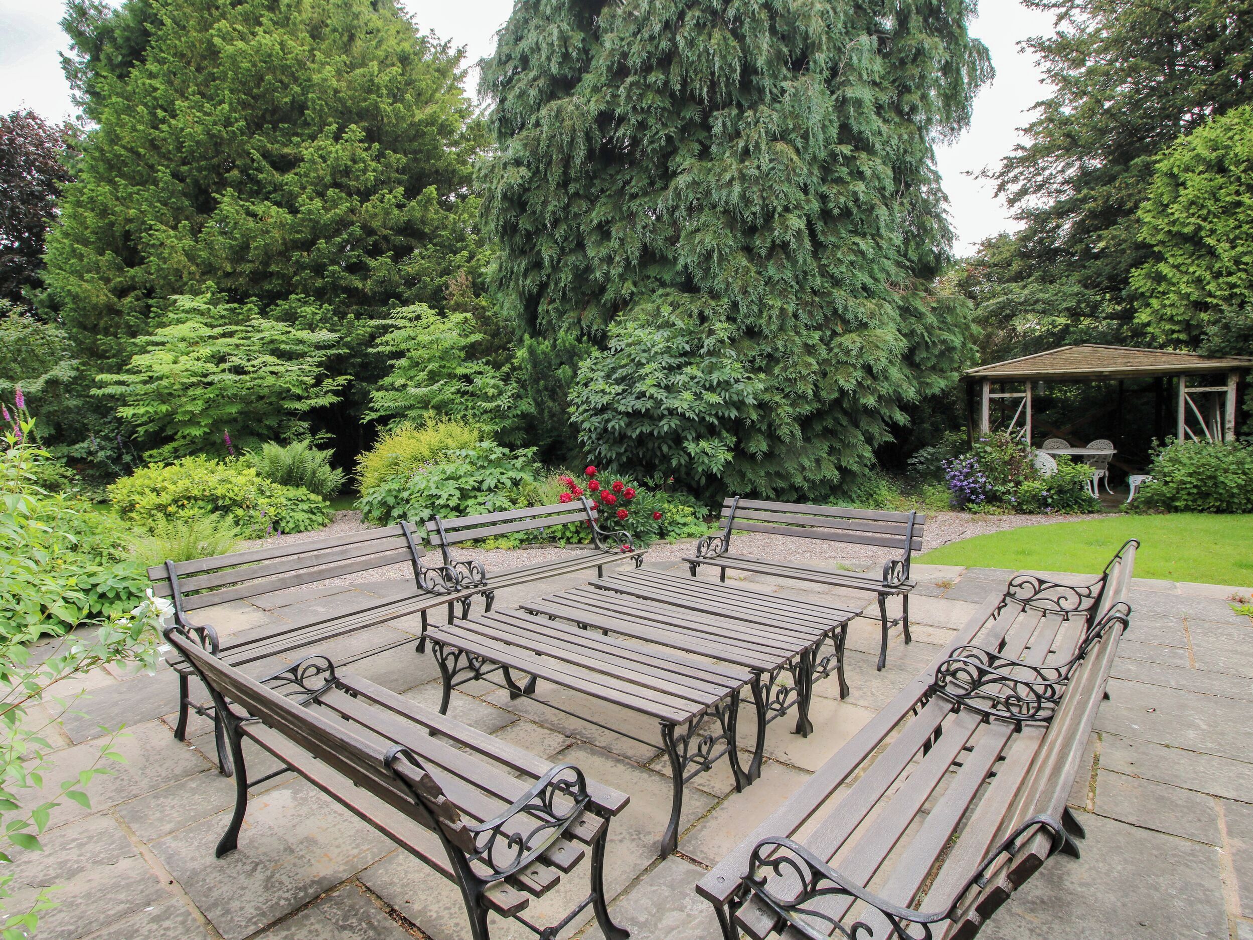A garden with a gazebo, benches, and a variety of trees.