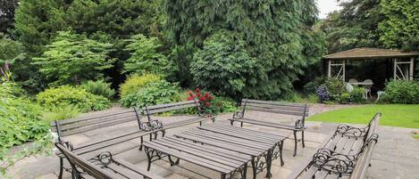 A garden with a gazebo, benches, and a variety of trees.