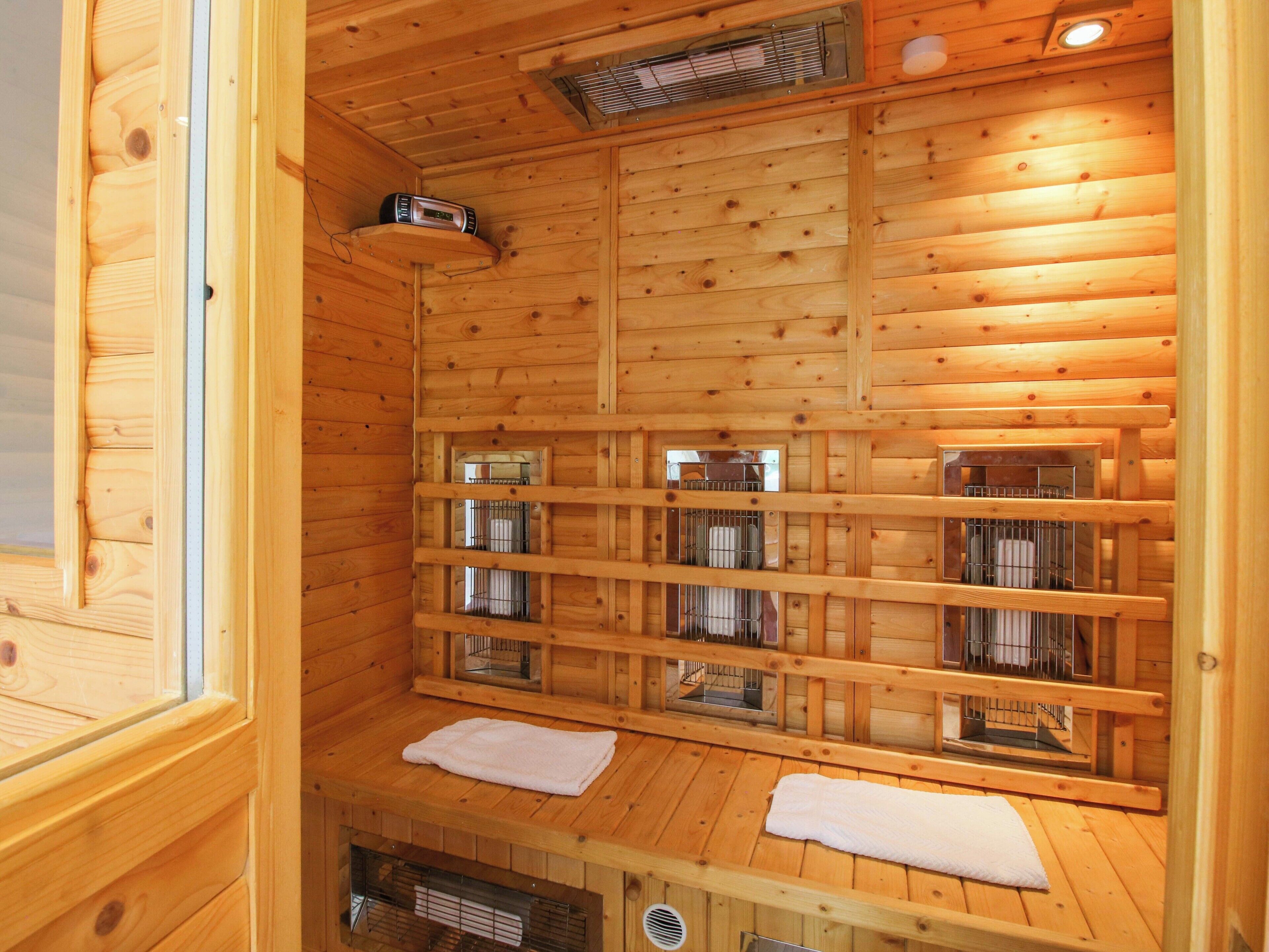A wooden sauna with multiple benches and metal cages, likely for heating stones.