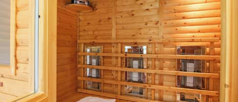 A wooden sauna with multiple benches and metal cages, likely for heating stones.