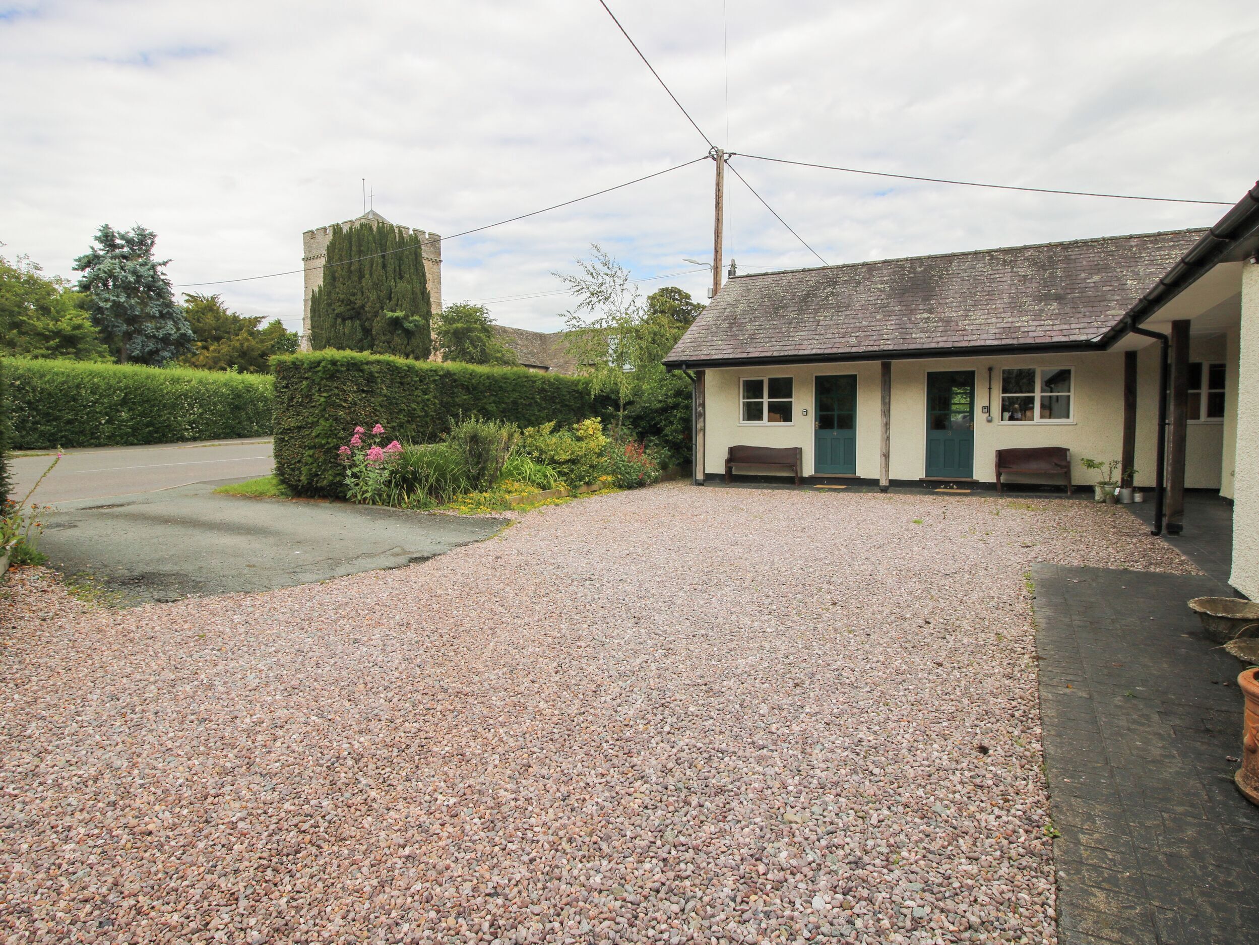 A building with a gravel driveway, a bench, and a small garden area.