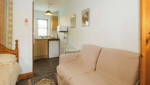 A compact room with a bed, a sofa, a kitchenette, and a small dining area. - Apartment 4 (Lydbury North)