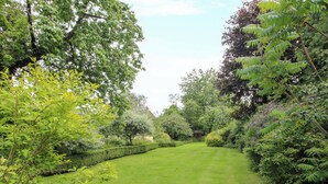 A well-maintained garden with a variety of trees and shrubs, a neatly trimmed hedge, and a clear pathway. - Apartment 4 (Lydbury North)