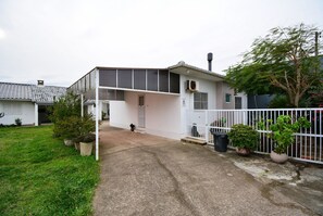 A two-story building with a covered patio area, a fenced yard, and potted plants. - Casa Aconchegante na Lagoa da Cigana (Laguna)