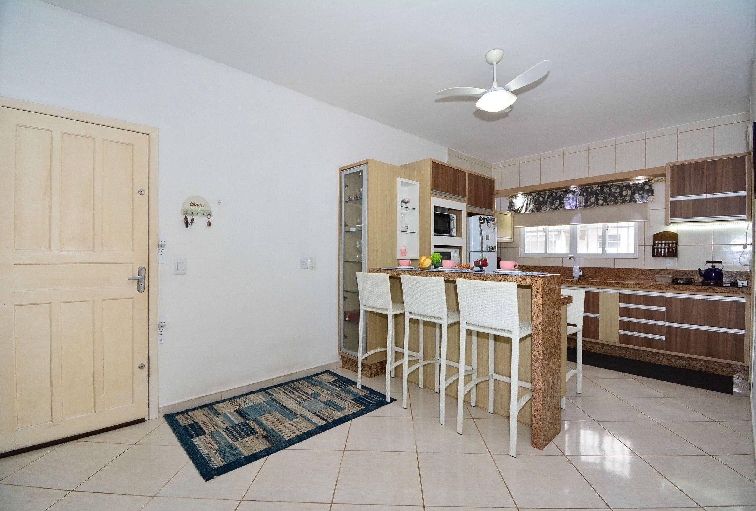 A kitchen with a bar area, a ceiling fan, and a door.
