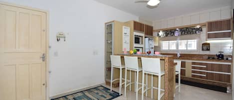 A kitchen with a bar area, a ceiling fan, and a door.