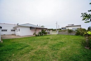 Um imóvel residencial com quintal cercado, varanda coberta e antena parabólica.