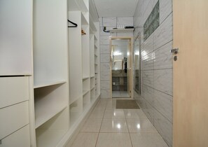 Um corredor com um guarda-roupa, um espelho e uma porta que dá para o banheiro.