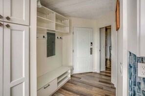Ein Korridor mit weißen Wänden, Holzboden, einer weißen Bank und einer Tür mit Schloss.