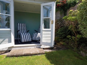 A room with two striped chairs, a door, and a small step leading to the entrance. - Marys House (Falmouth)