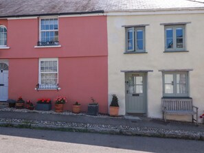 A two-story building with a red and cream facade, multiple windows, and a bench outside. - Marys House (Falmouth)