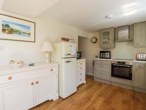 A kitchen with white cabinets, a refrigerator, a microwave, a toaster, and a clock on the wall. - Marys House (Falmouth)