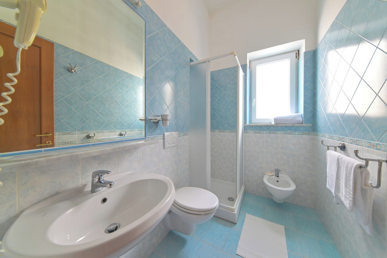 Une salle de bain équipée d’un lavabo, de toilettes, d’un bidet et d’un espace douche.