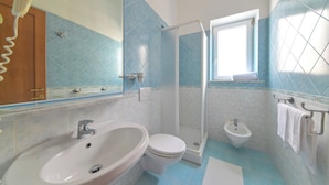Une salle de bain équipée d’un lavabo, de toilettes, d’un bidet et d’un espace douche.