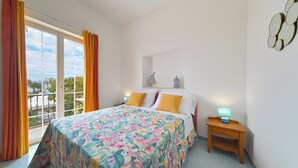 Une chambre à coucher avec un grand lit, une table de chevet, une fenêtre avec des rideaux et une vue sur l’extérieur.