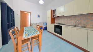 Une cuisine de taille réduite comprenant une table à manger, des chaises, une cuisinière et des placards.