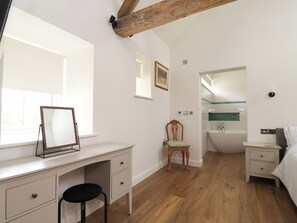 Ein Schlafzimmer mit Schreibtisch, Stuhl, Bett und einem Badezimmer mit Badewanne.