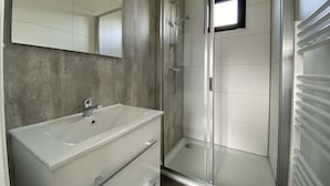 A modern bathroom with a glass shower enclosure, a white sink, and a large mirror. - Just Nature Light 4 (Kampen)