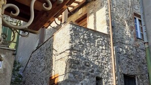 Un bâtiment en pierre avec une porte en bois et une rambarde en métal.