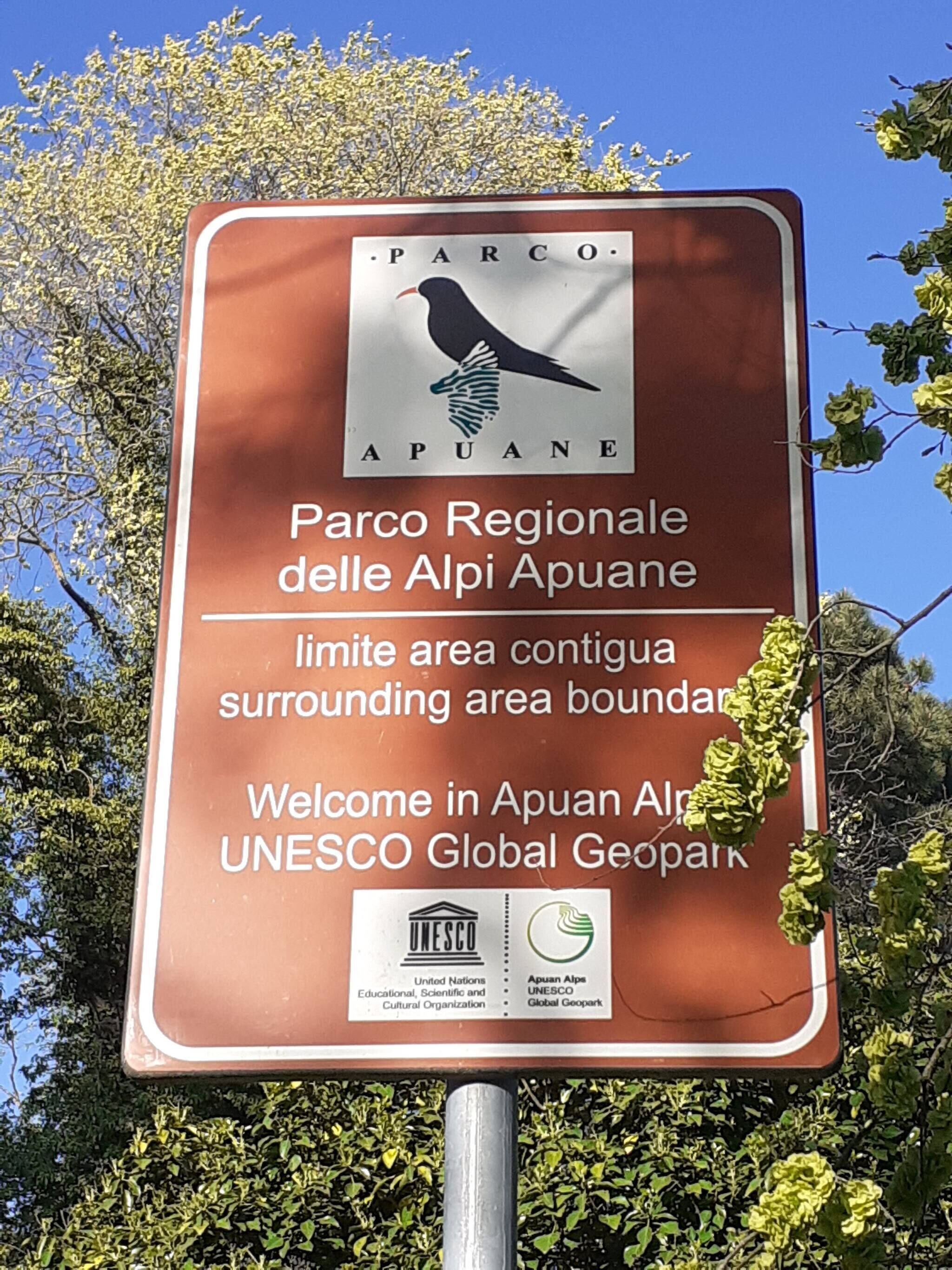 Un cartel con el logotipo de Parco Regionale delle Alpi Apuane, dando la bienvenida a visitantes al Geoparque Global de la UNESCO.
