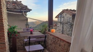 Une terrasse extérieure avec une table et des chaises, une lanterne et une bougie posées sur un mur de pierre.
