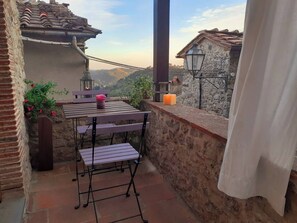 Eine Terrasse im Freien mit Tisch, Stühlen, einem Laternen und einer Kerze an einer Steinmauer.