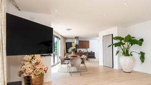En modern inredning med ett matområde, kök och en stor krukväxt.