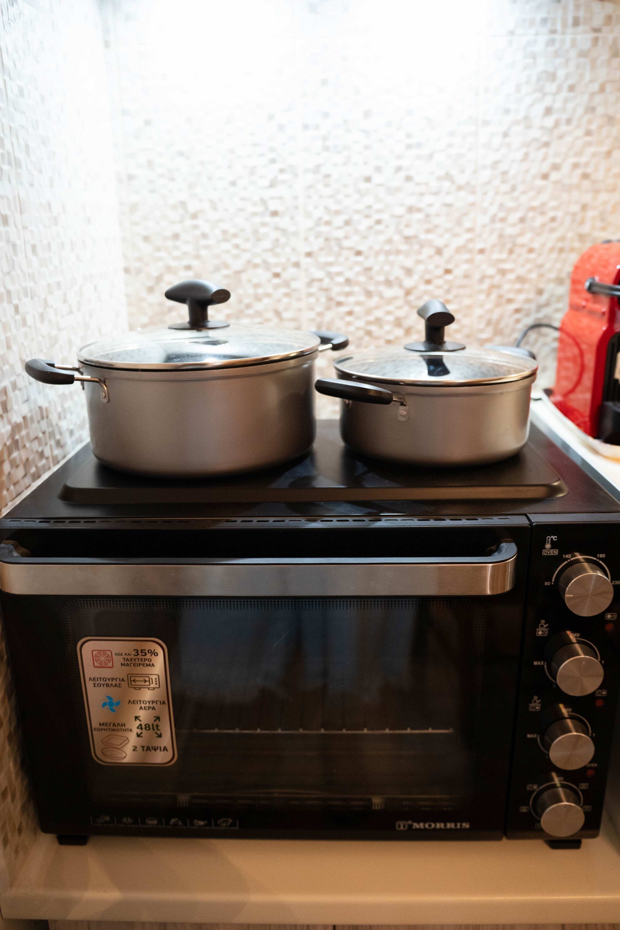 Una cocina con estufa y dos ollas encima.