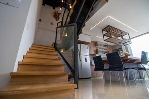 A modern kitchen with a built-in refrigerator, wooden staircase, and a dining area with chairs and a table. - Amplio ático con vistas, jacuzzi a 15 min de Provenza (Itagüí)