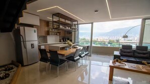 A modern kitchen with a dining area, large windows, and a city view. - Amplio ático con vistas, jacuzzi a 15 min de Provenza (Itagüí)