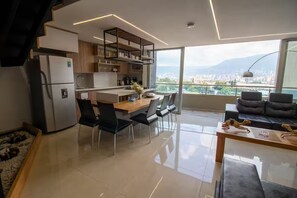 A modern kitchen with a dining area, large windows, and a city view. - Amplio ático con vistas, jacuzzi a 15 min de Provenza (Itagüí)